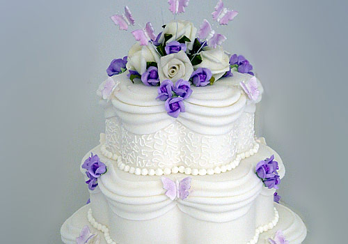 A traditional 3-tier Wedding Cake with flowers and lace